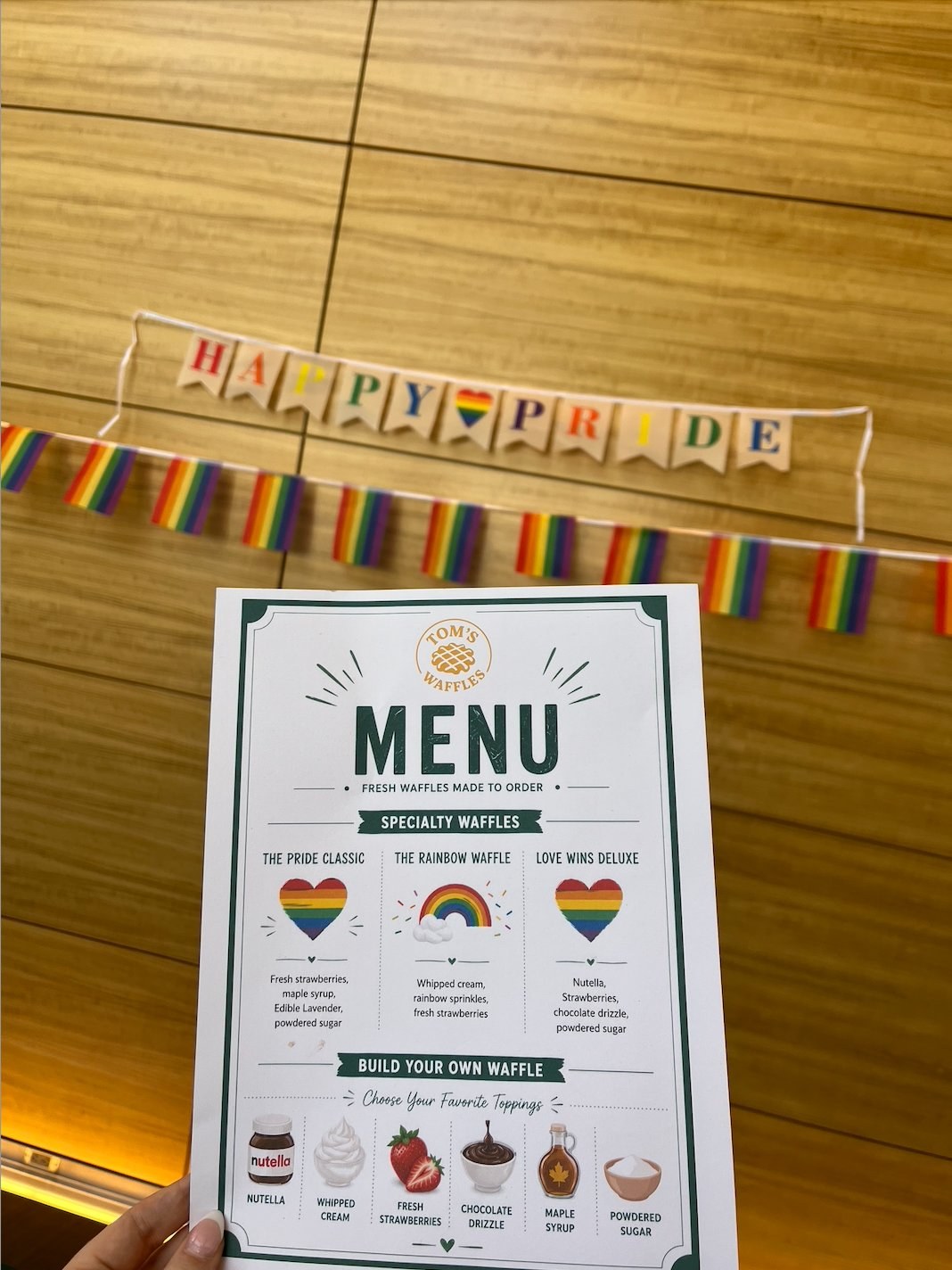 Tom's Waffles Pride menu with Happy Pride banner and rainbow flags