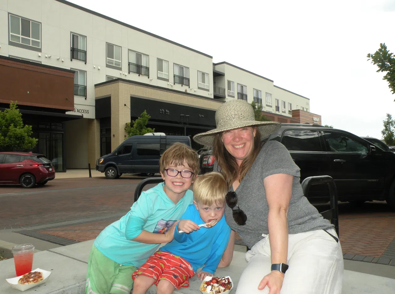 Family enjoying fresh waffles and drinks at an outdoor Denver community event catered by Tom's Waffles