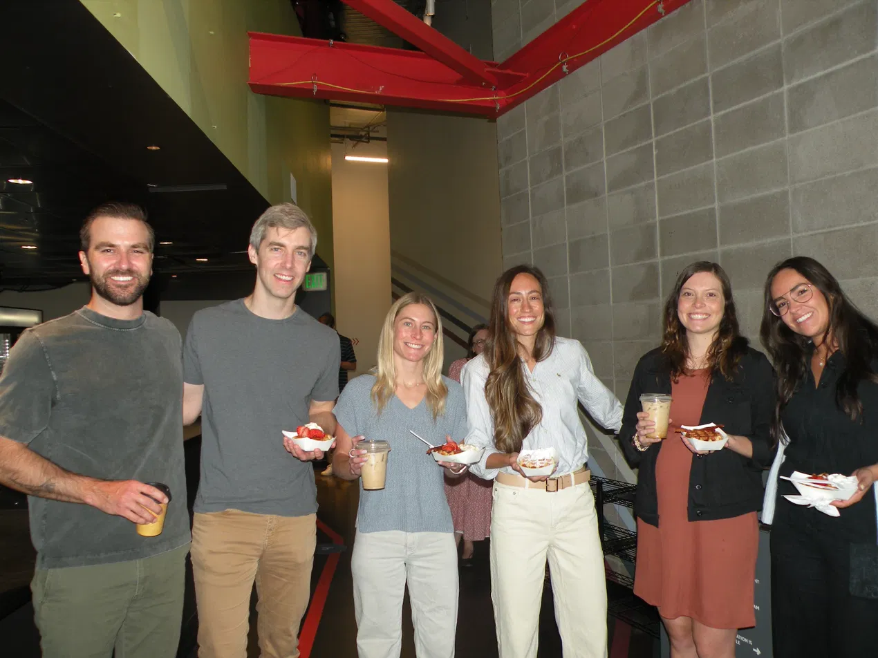 Happy staff holding fresh Belgian waffles and espresso drinks at a Tom's Waffles corporate catering event in Denver