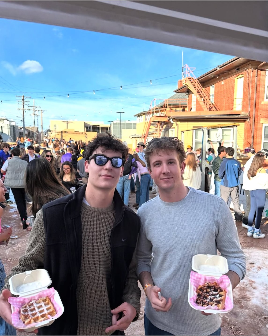 Two students holding fresh Tom's Waffles at a Boulder college event