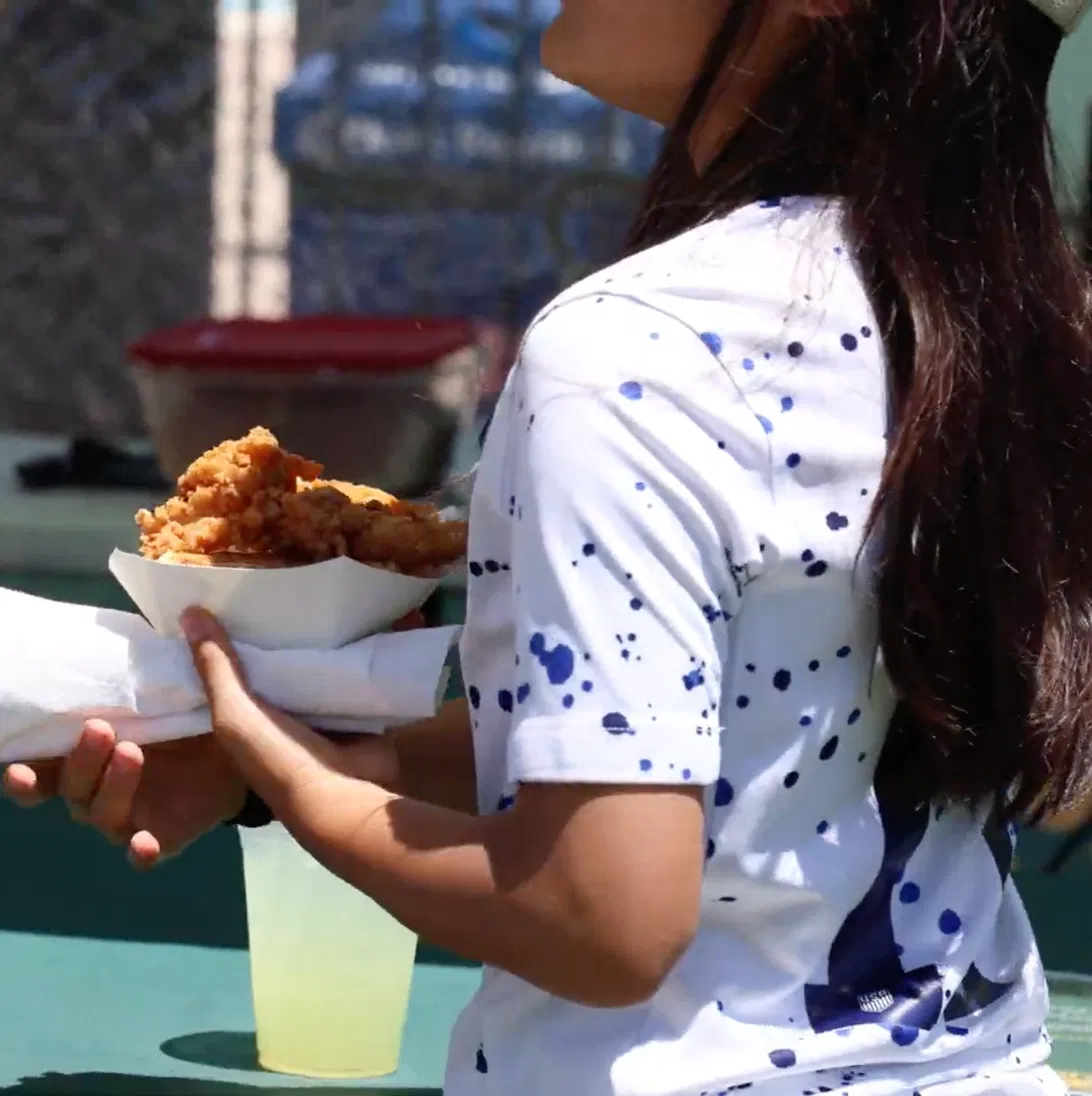 Guest holding a fresh-fried chicken tender basket from Tom's Waffles catering