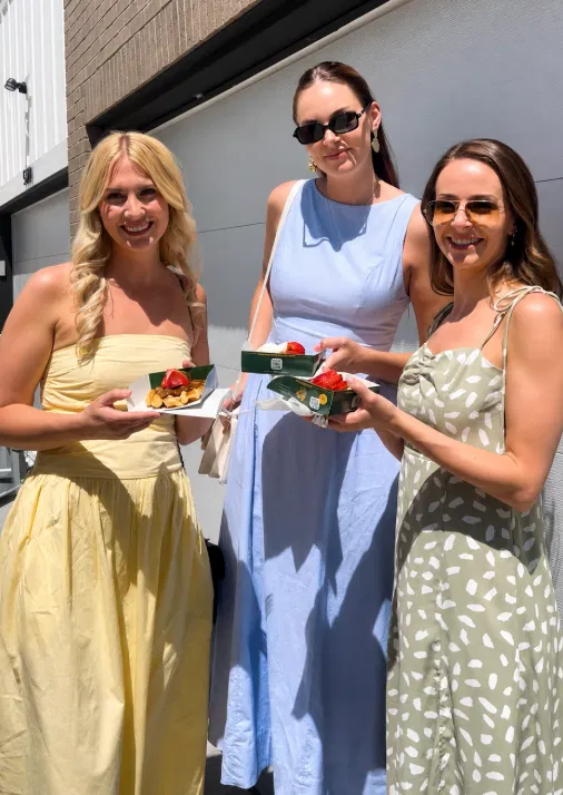 Women in dresses enjoying fresh Belgian waffles at a Tom's Waffles bridal shower in Denver