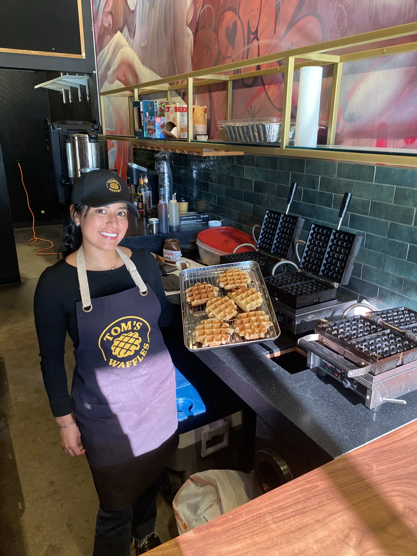 A crew member holding a tray of fresh waffles at an indoor event