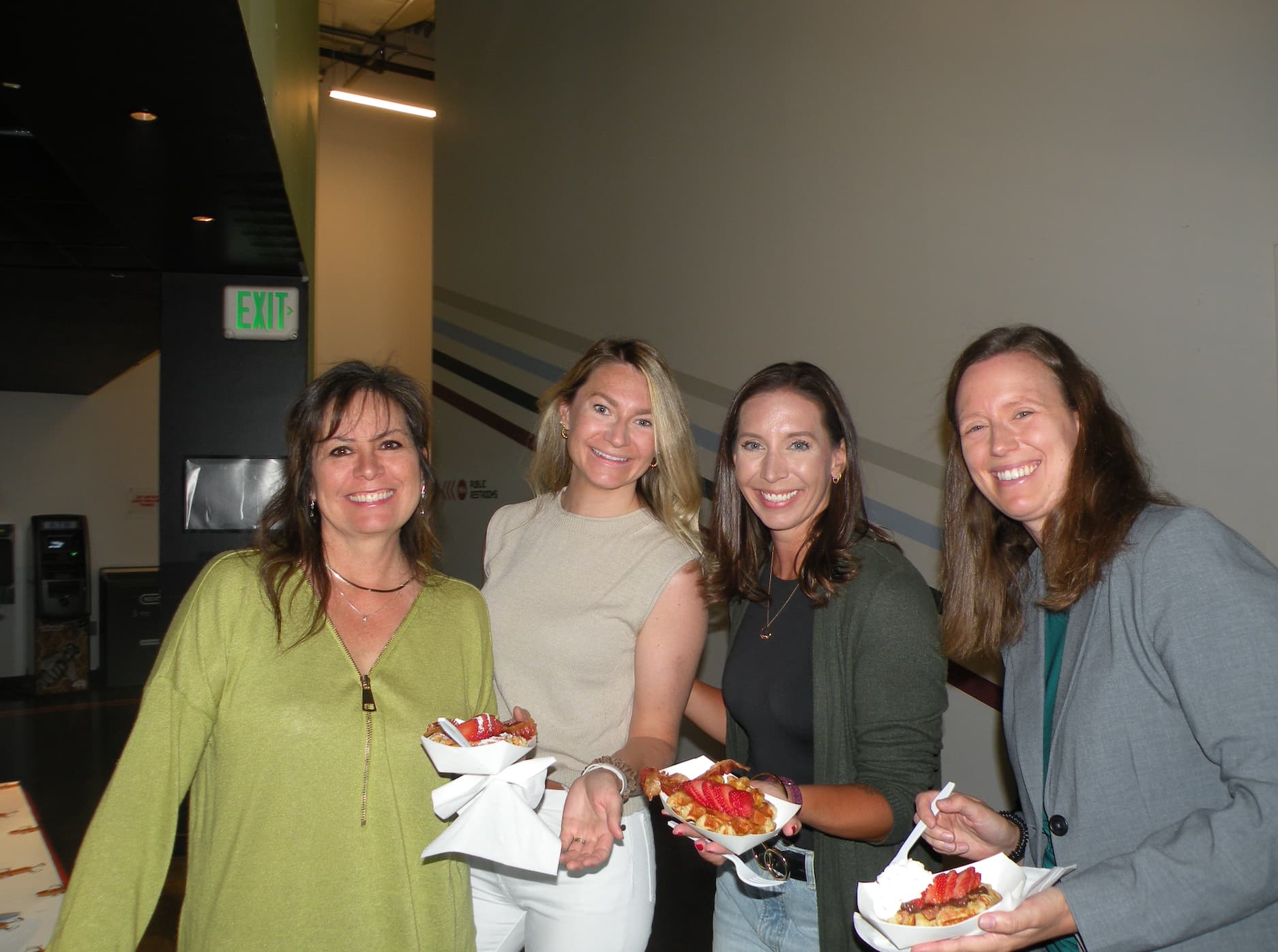 Guests holding fresh Belgian waffles with strawberries at a Denver holiday party catered by Tom's Waffles
