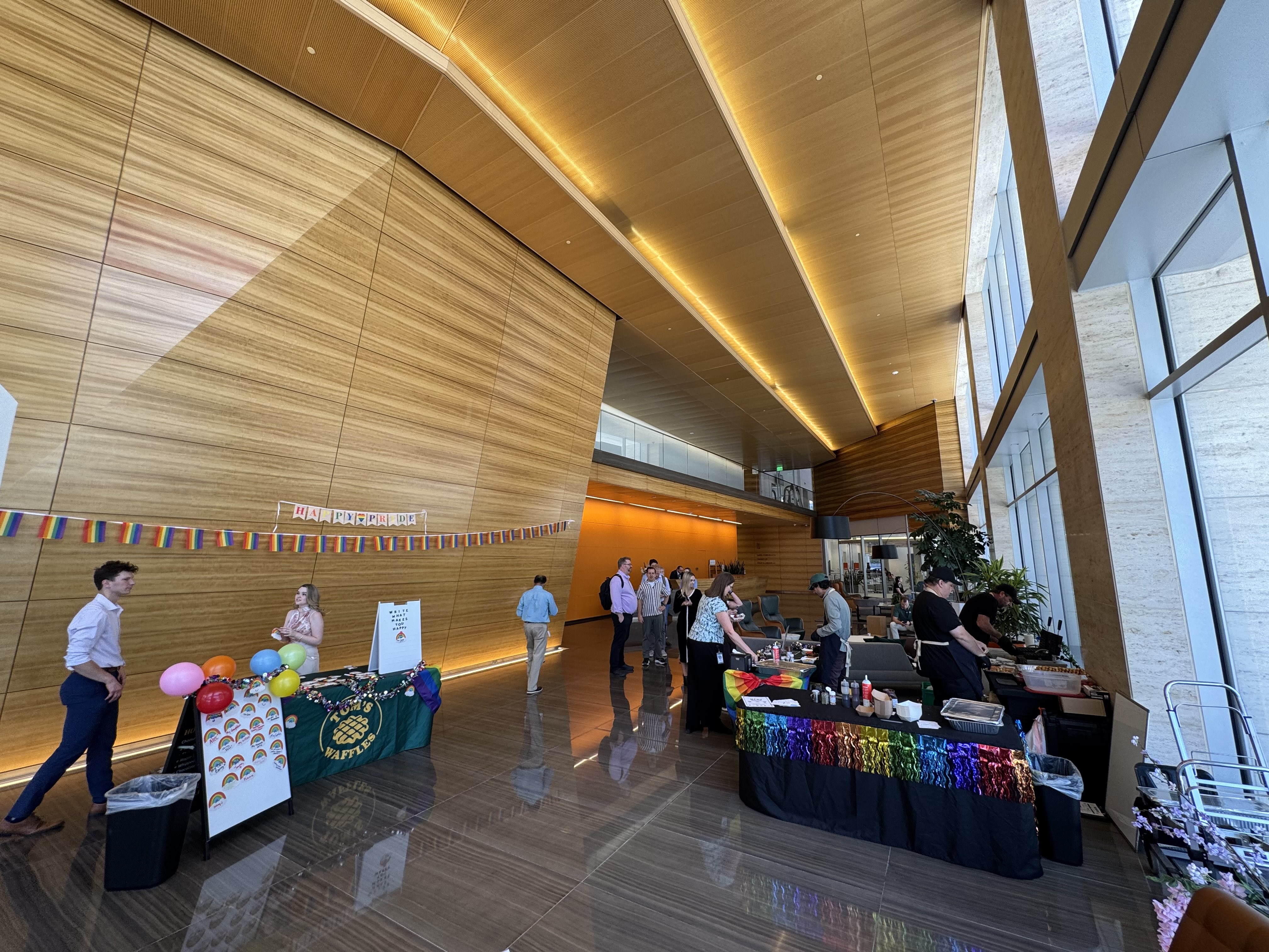 Our Pride-decorated waffle station and a card table in a tall office lobby